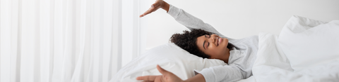 Afbeelding van een jonge vrouw in bed, die zich uitrekt